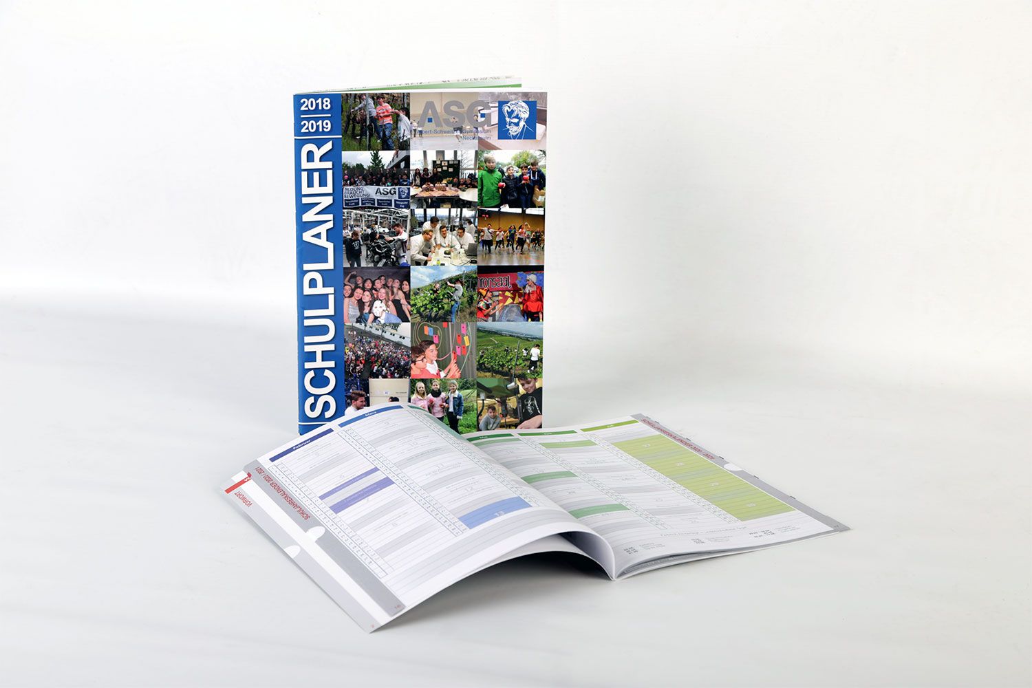 Schulplaner frontal mit Cover-Ansicht und ein Weiterer aufgeschlagen davor